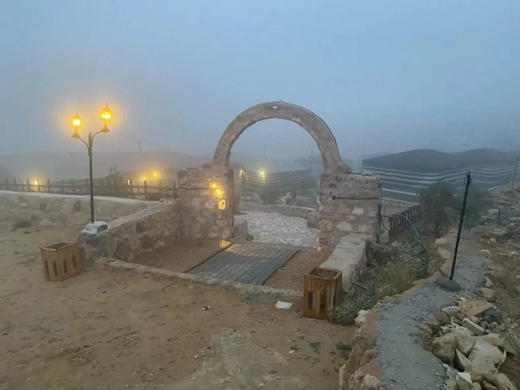 Stone arch and lamp posts at the camp entrance on a misty morning