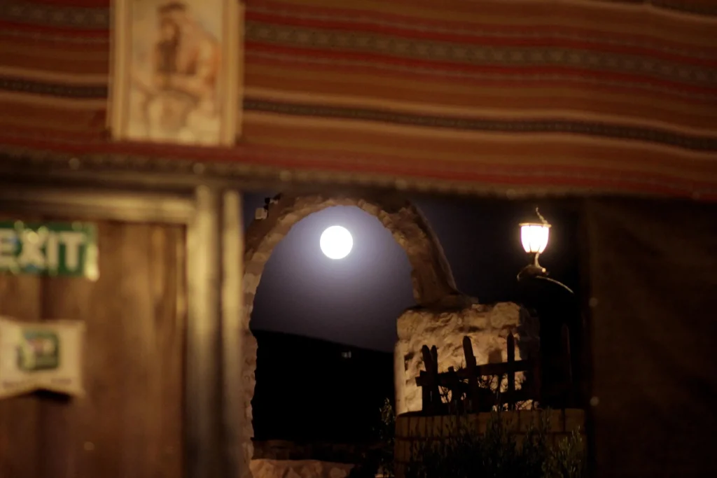 Stone archway at Petra Wassaif Camp under a bright moon at night