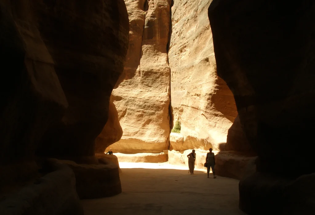 Walkers in the narrow sandstone Siq canyon leading into Petra