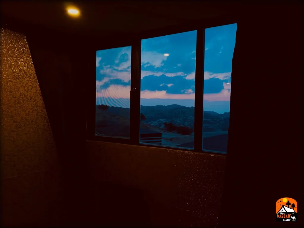 View of the Petra mountains at dusk through a room window at the camp